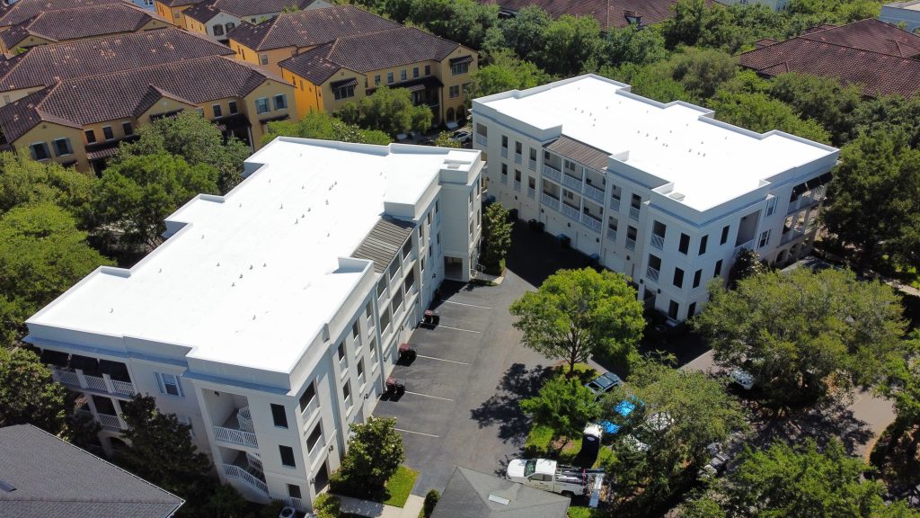 Aerial view of a white TPO flat roof coating completed on a multi-story commercial apartment building in Central Florida
